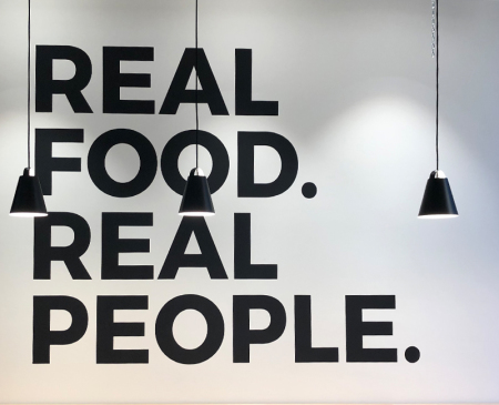 Große Buchstaben, gesprüht mit Schablonen foli an eine weiße Innenwand eines Restaurants von Motiv-Wunsch in Berlin.