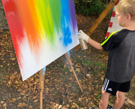 Ein Graffiti Workshop von Motiv-Wunsch mit Jugendlichen in Stahnsdorf. Ein Junge sprüht auf eine Leinwand.