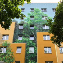 Auf einem Neubaublock, oder einer Platte, gesprühtes Illusionsbild mit Häusern und Bäumen. In Brandenburg von Motiv-Wunsch.