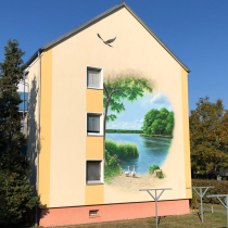 Dekorative Malerei einer realistischen Landschaft in Elstal auf einer Fassade für eine WBG (Wohnungsbaugenossenschaft) von Motiv-Wunsch.