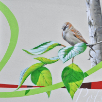 Auf einer Fassade in Stahnsdorf ist ein Spatz gesprüht, er sitzt auf einem Ast mit grünen Blättern. Ein Wandbild von Motiv-Wunsch.