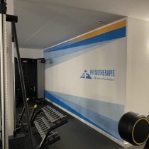 In einem Fitnessstudio sind farbige Streifen, stilvolle Elemente und das Logo an die Wand gesprüht von Motivwunsch, Mario Winkler.